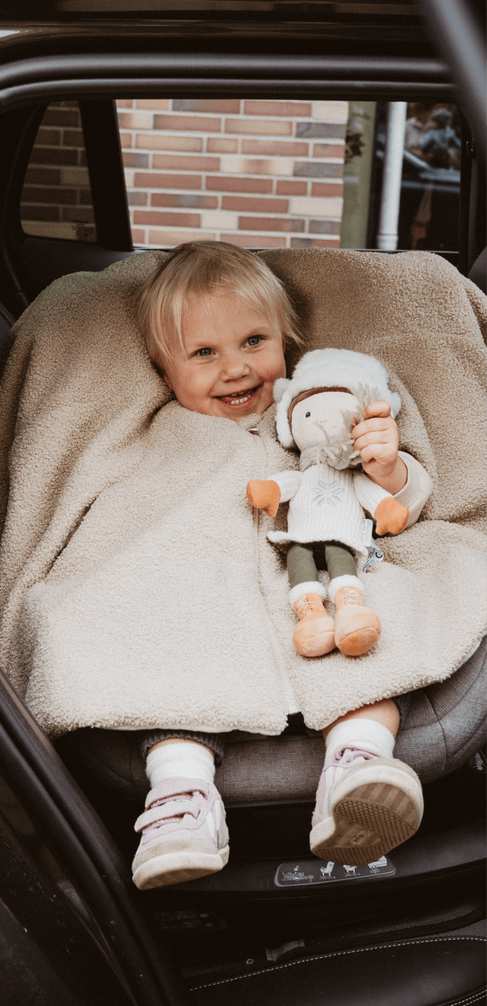 Warm eingekuschelt im Zwergperten-Poncho: Mädchen im Reboarder auf der Rückbank