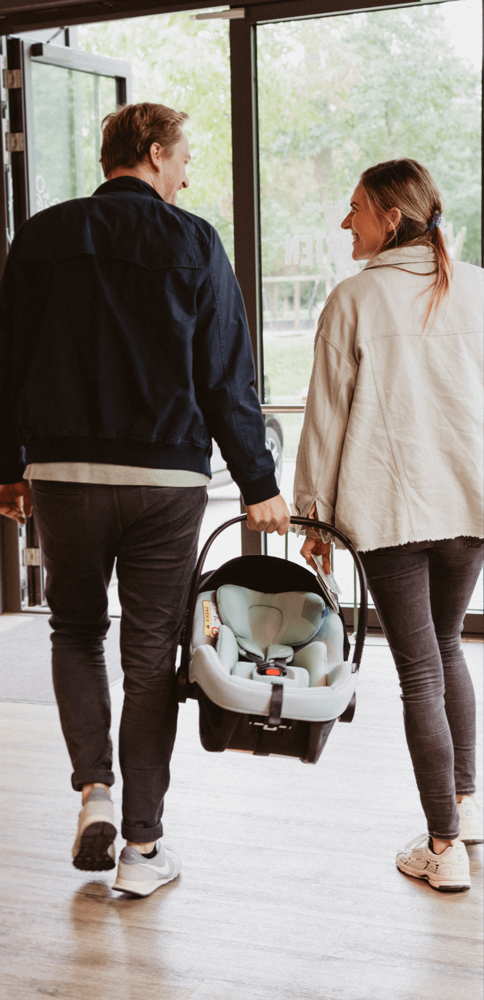 Junges Paar verlässt den Store mit einer Babyschale in der Hand